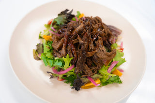 A picture of a healthy meal, featuring pulled beef brisket and a salad.